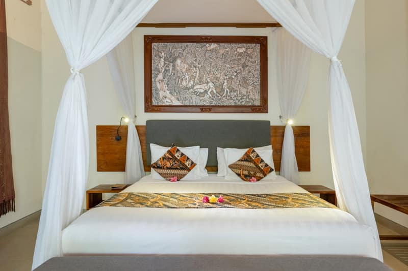 Elegant bedroom with wooden floors and mosquito net at our ubud luxury villa.